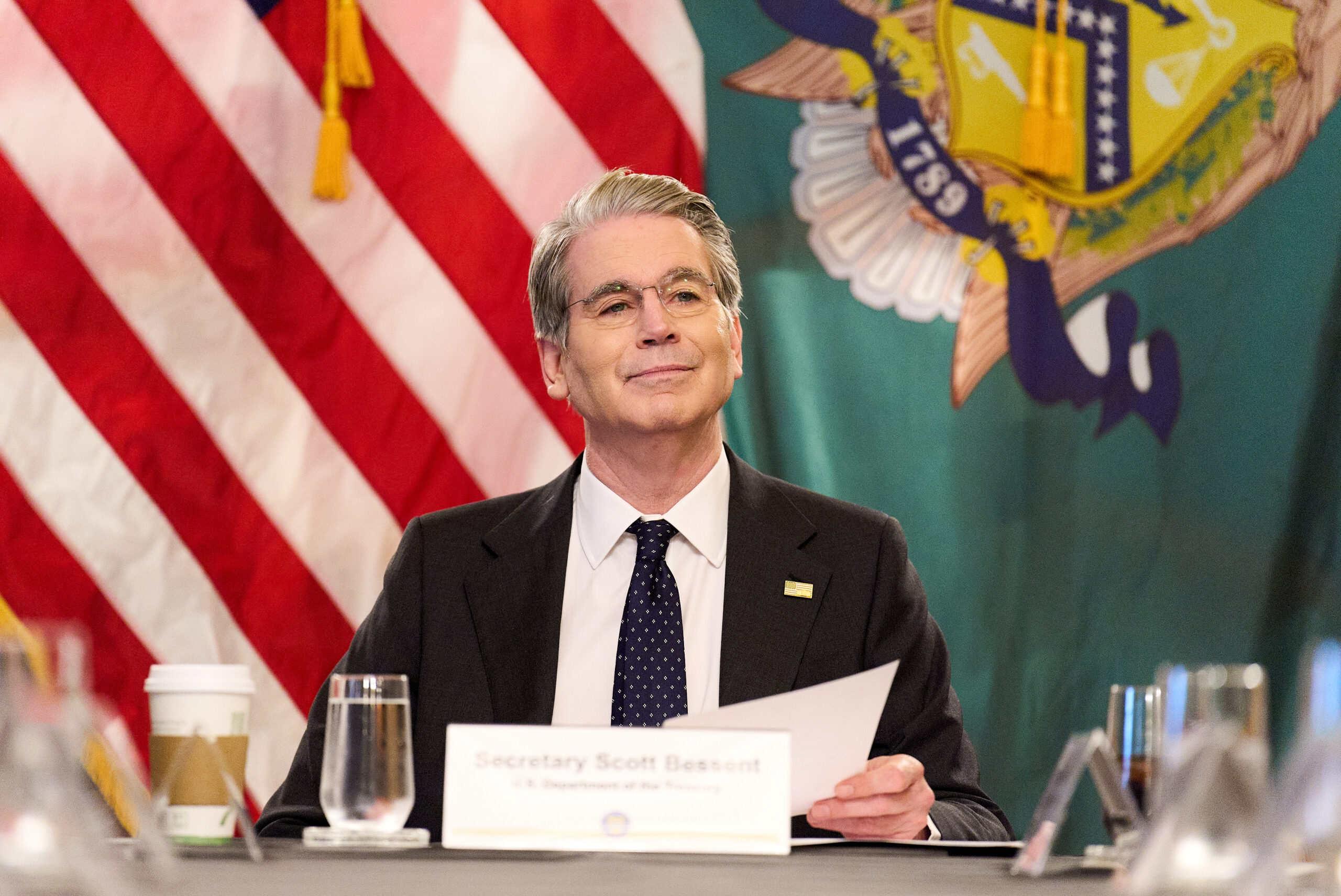 Treasury Secretary Scott Bessent speaking at a podium, looking determined.