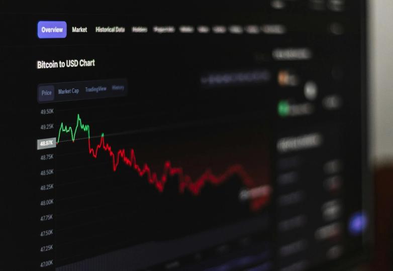 A graphic showing Bitcoin symbol with a downward arrow, contrasted with upward trending stock market charts.