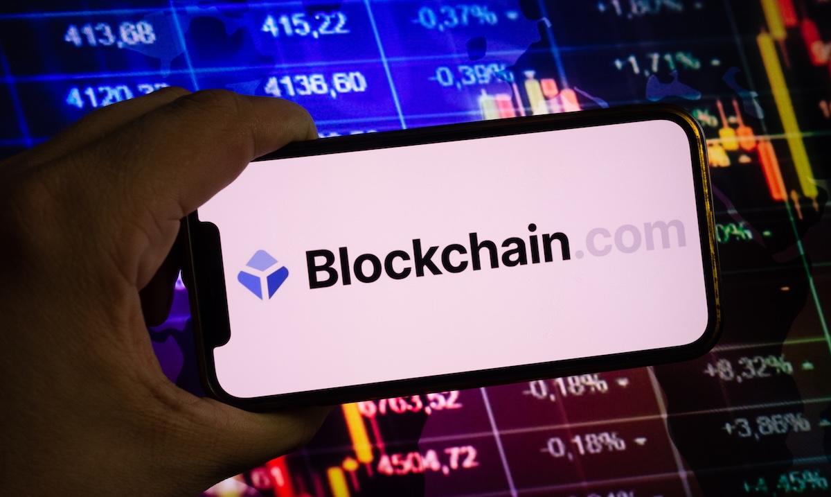 A stylized image of the Blockchain.com logo against a backdrop of digital circuit board patterns and stock market charts, suggesting a blend of technology and finance.