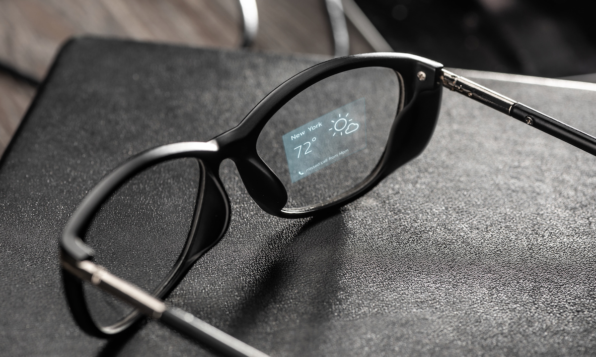 Sleek AI-powered smart glasses on a modern desk with holographic overlays