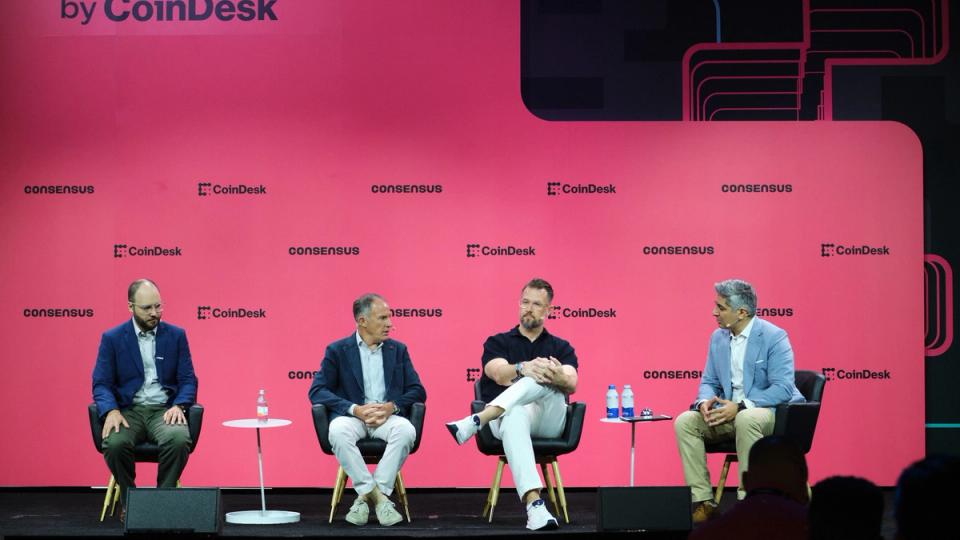 A group of business executives speaking on a panel at a conference, with a banner in the background that reads 'Consensus Miami 2026'.