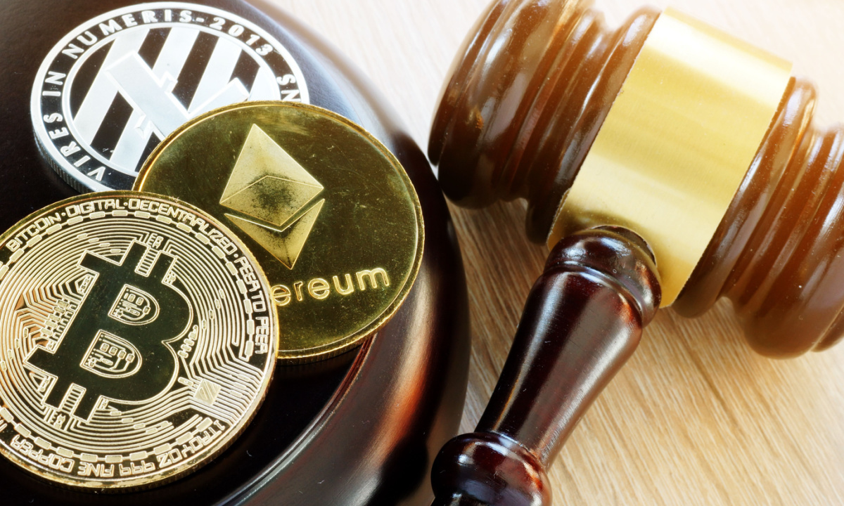 A gavel striking a block with cryptocurrency symbols on it, representing regulatory action.
