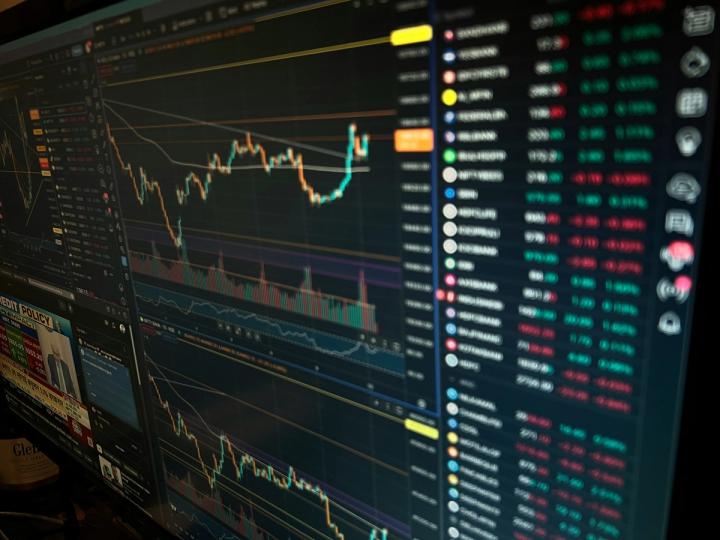 A smartphone screen displaying cryptocurrency charts with a downward trend and geopolitical news headlines in the background.