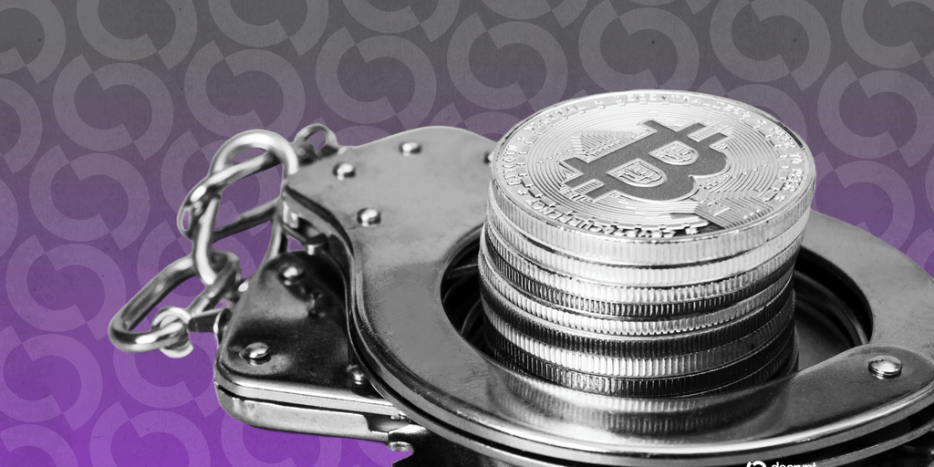 Australian police officers standing near a table with seized electronics and a Bitcoin logo.